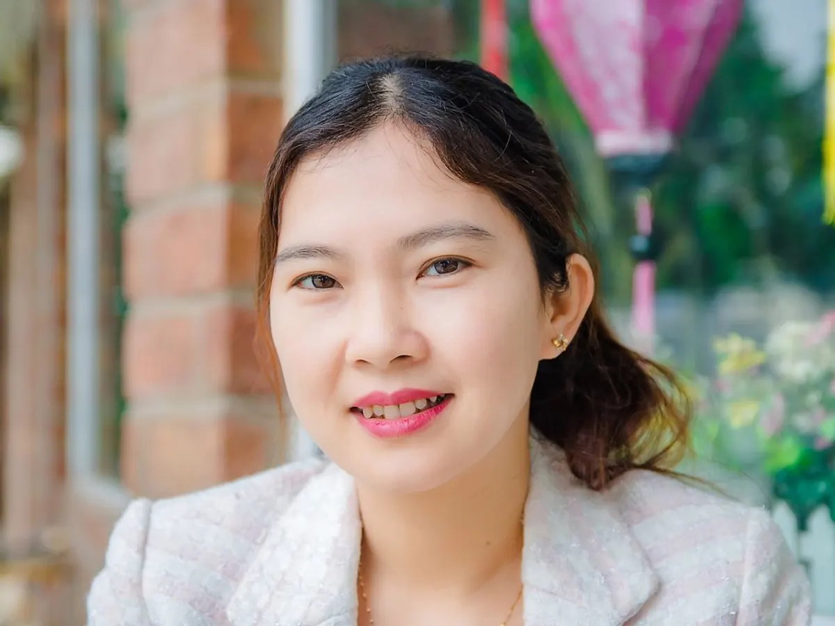 Perempuan muda tersenyum hangat di luar ruangan
