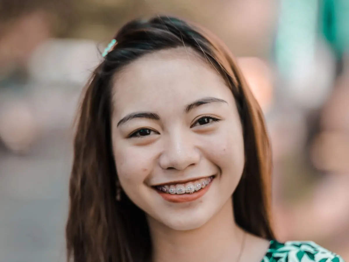 Perempuan muda tersenyum lebar dengan behel di gigi